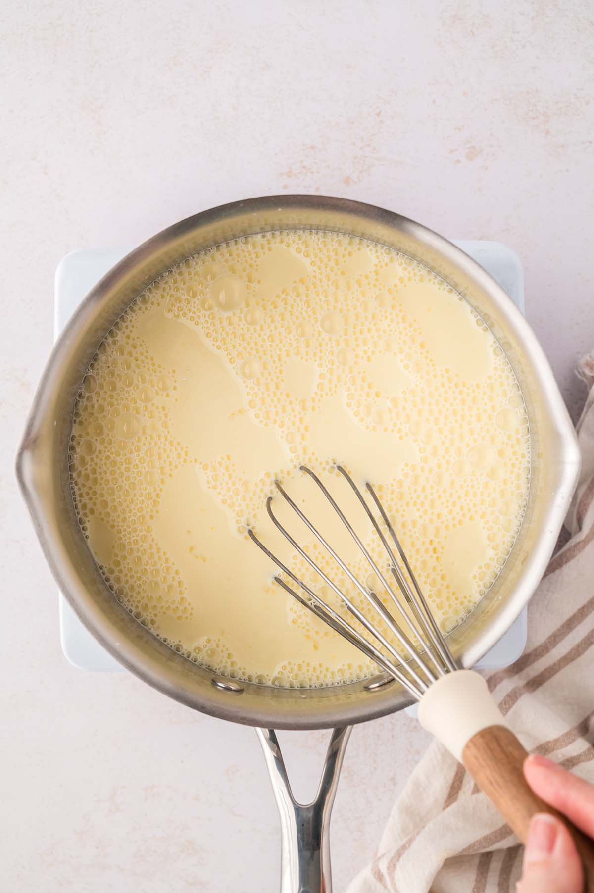 yellow thin liquid in a saucepan with a whisk.