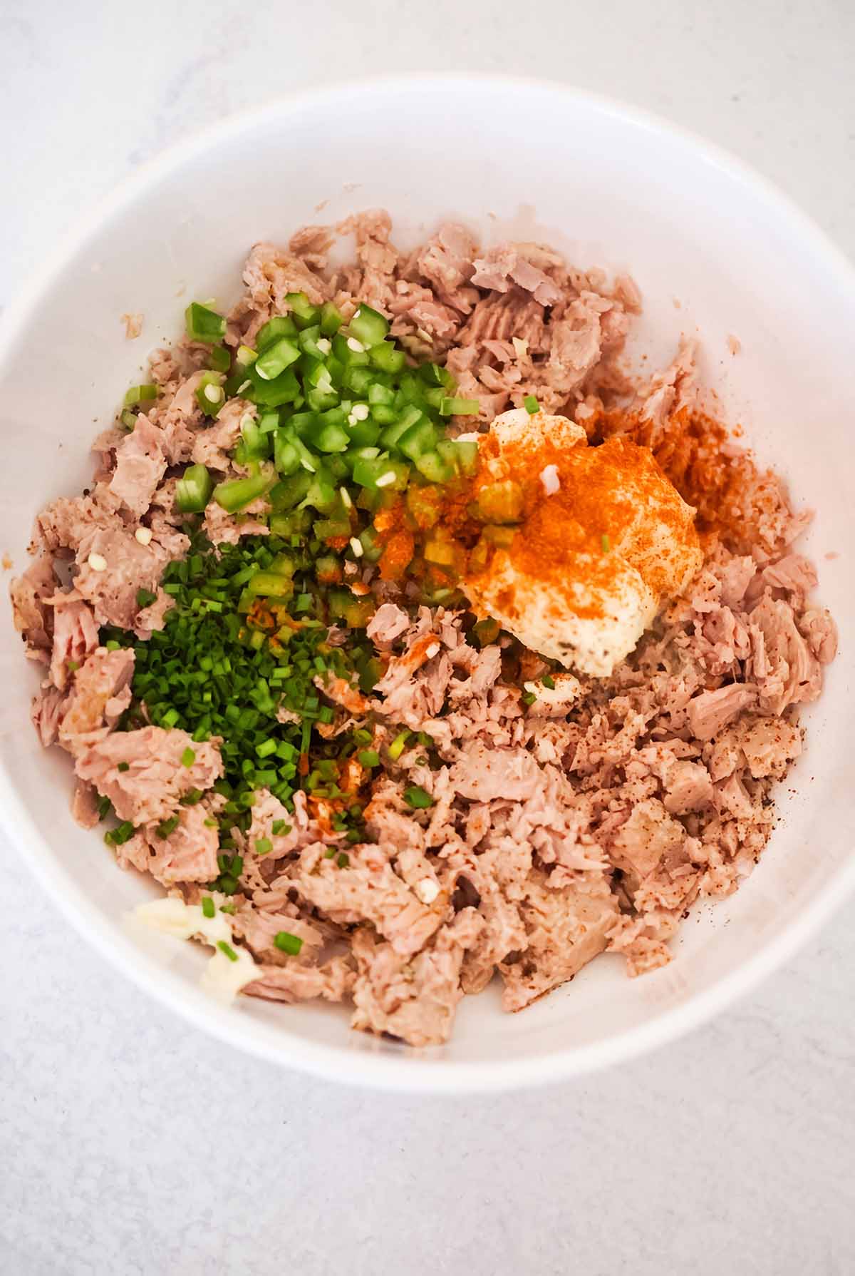 canned tuna, mayo, jalapeños, chives, and cayenne pepper in a white bowl.