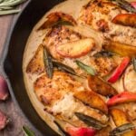 brown butter chicken in a black skillet with apples and sage.