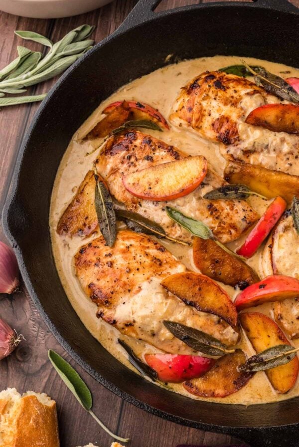 brown butter chicken in a black skillet with apples and sage.