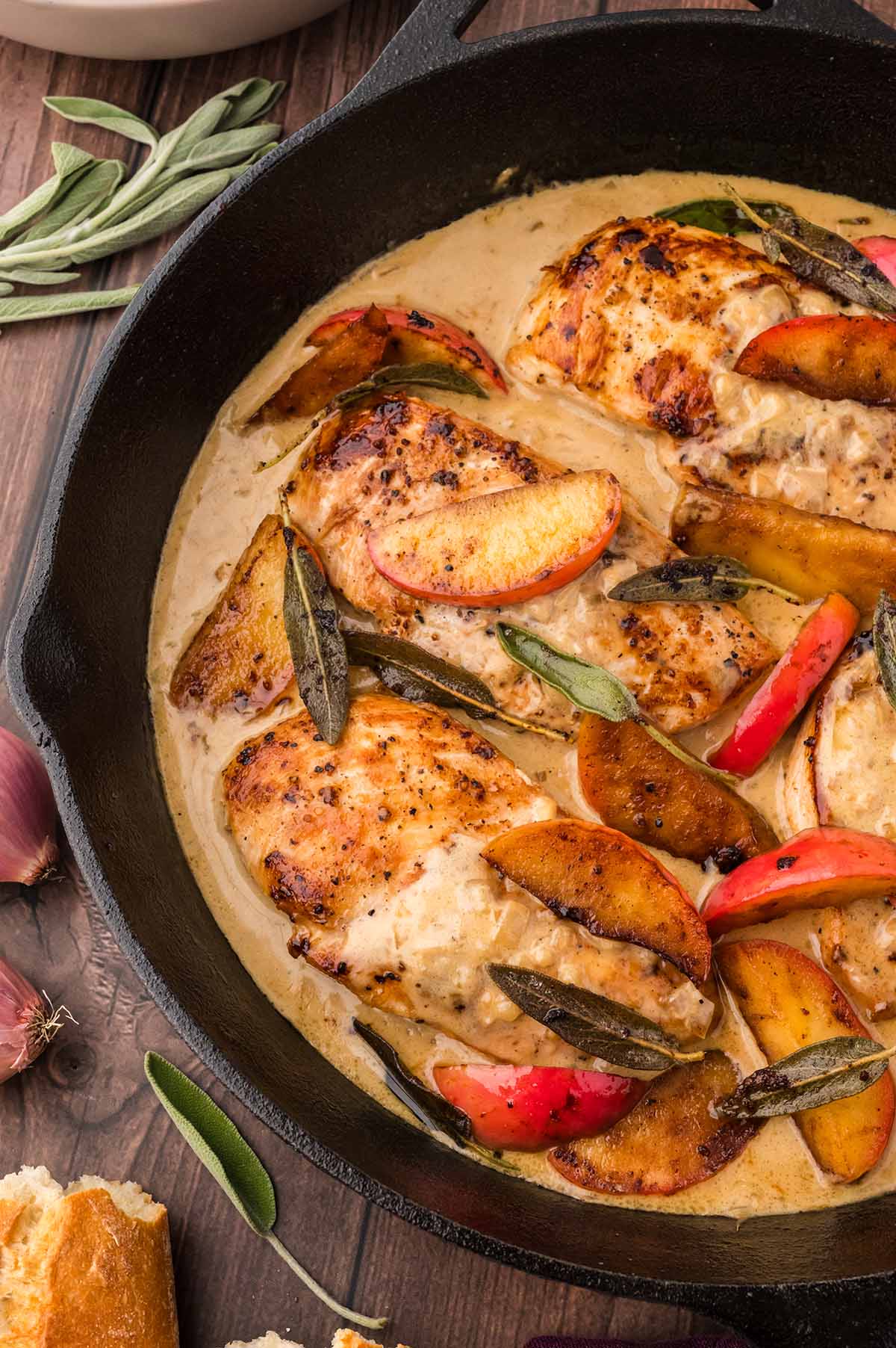 brown butter chicken in a black skillet with apples and sage.