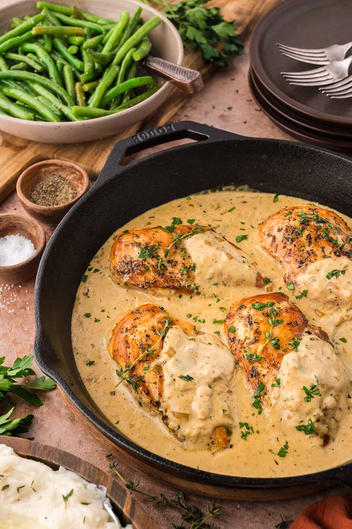 Boursin chicken in a skillet with a bowl of green beans on the side.