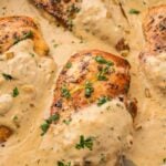 creamy Boursin chicken breasts in a skillet with fresh herbs on top.