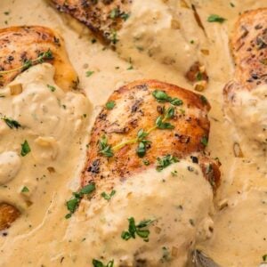 creamy Boursin chicken breasts in a skillet with fresh herbs on top.