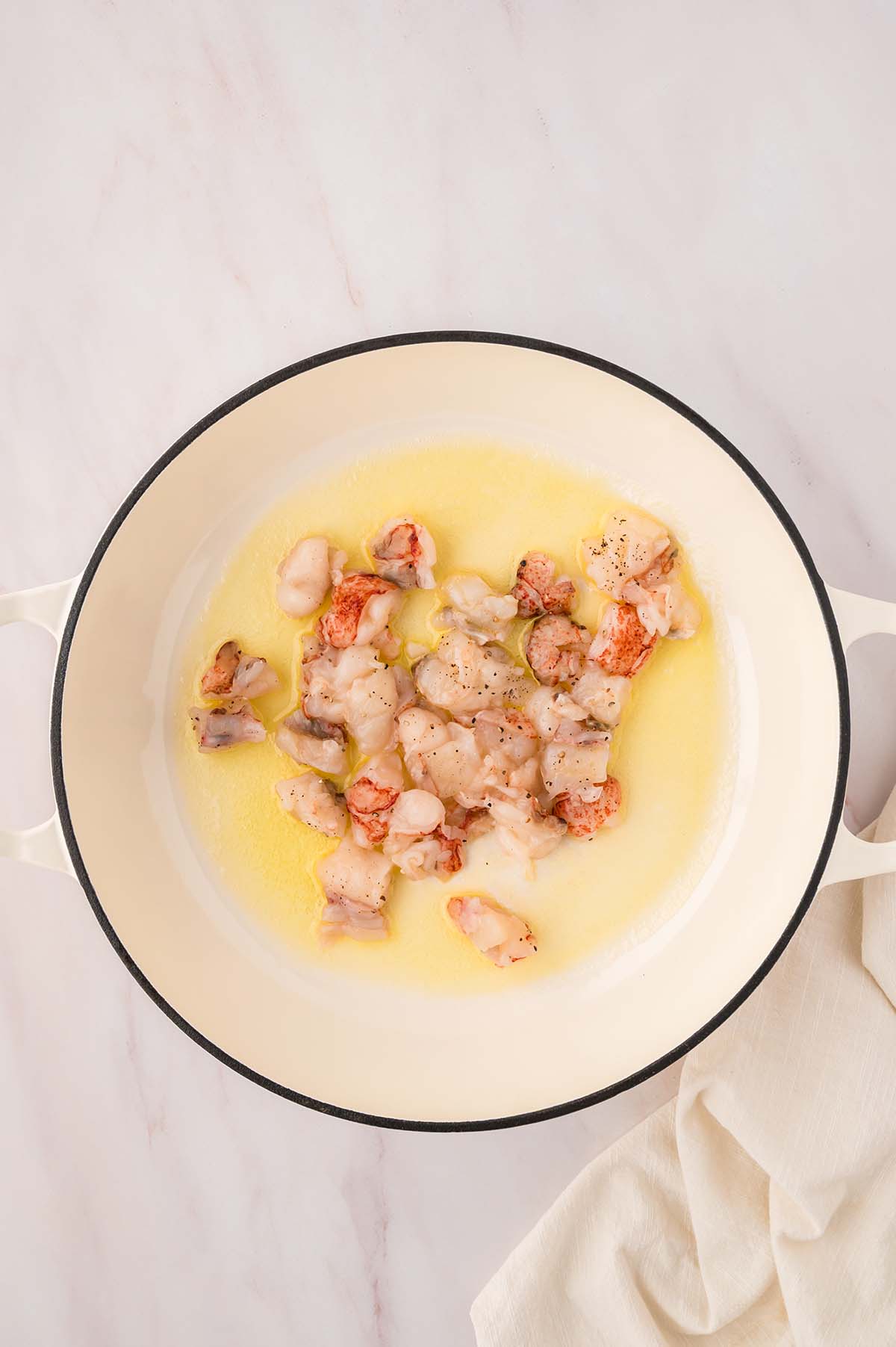 raw lobster tail chunks cooking in oil and butter.