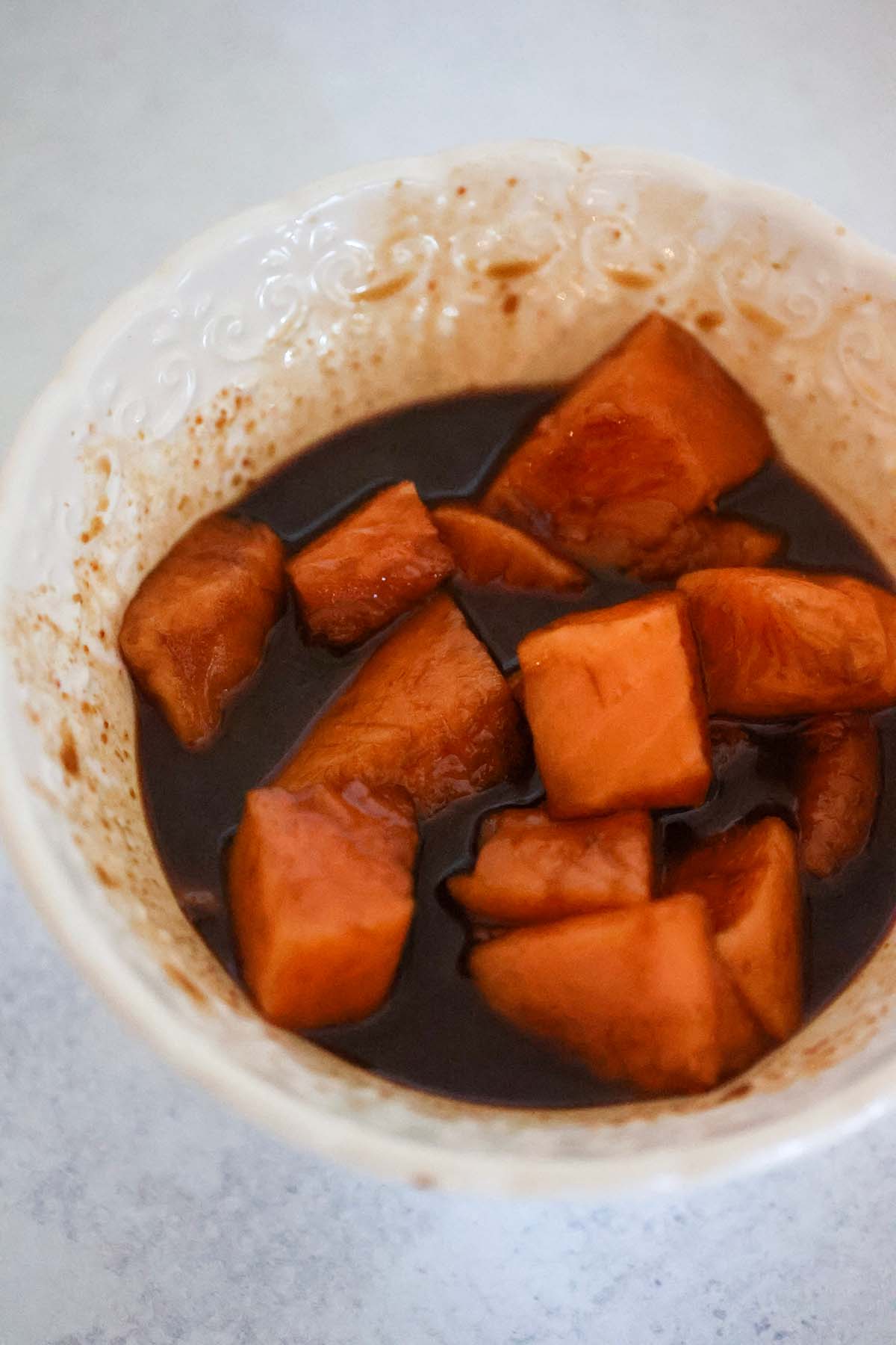 raw salmon chunks with sauce in a bowl.