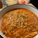 a spicy tomato chicken orzo soup with candles in the background.