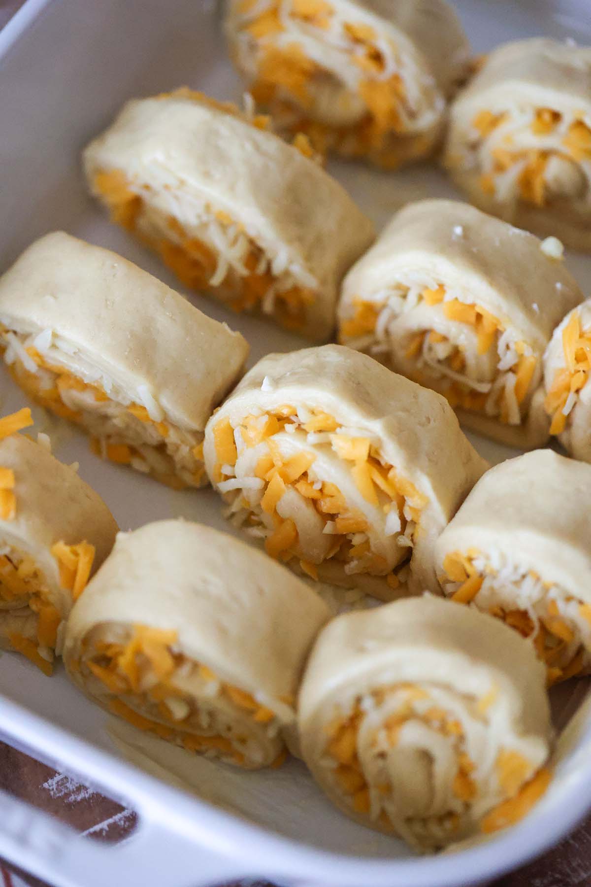 12 unbaked cheese rolls in a baking dish.