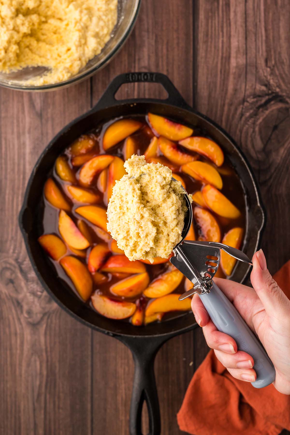 a scoop of cornbread batter on top of peaches.