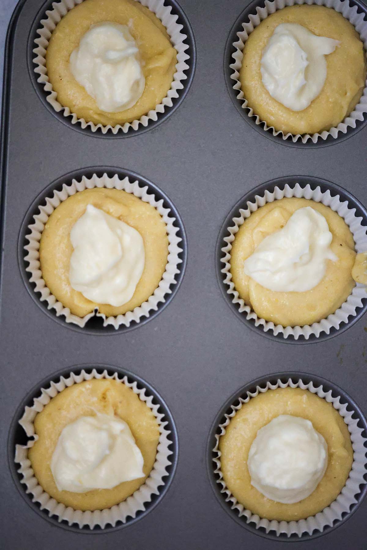muffin tin filled with cornbread batter and cream cheese.