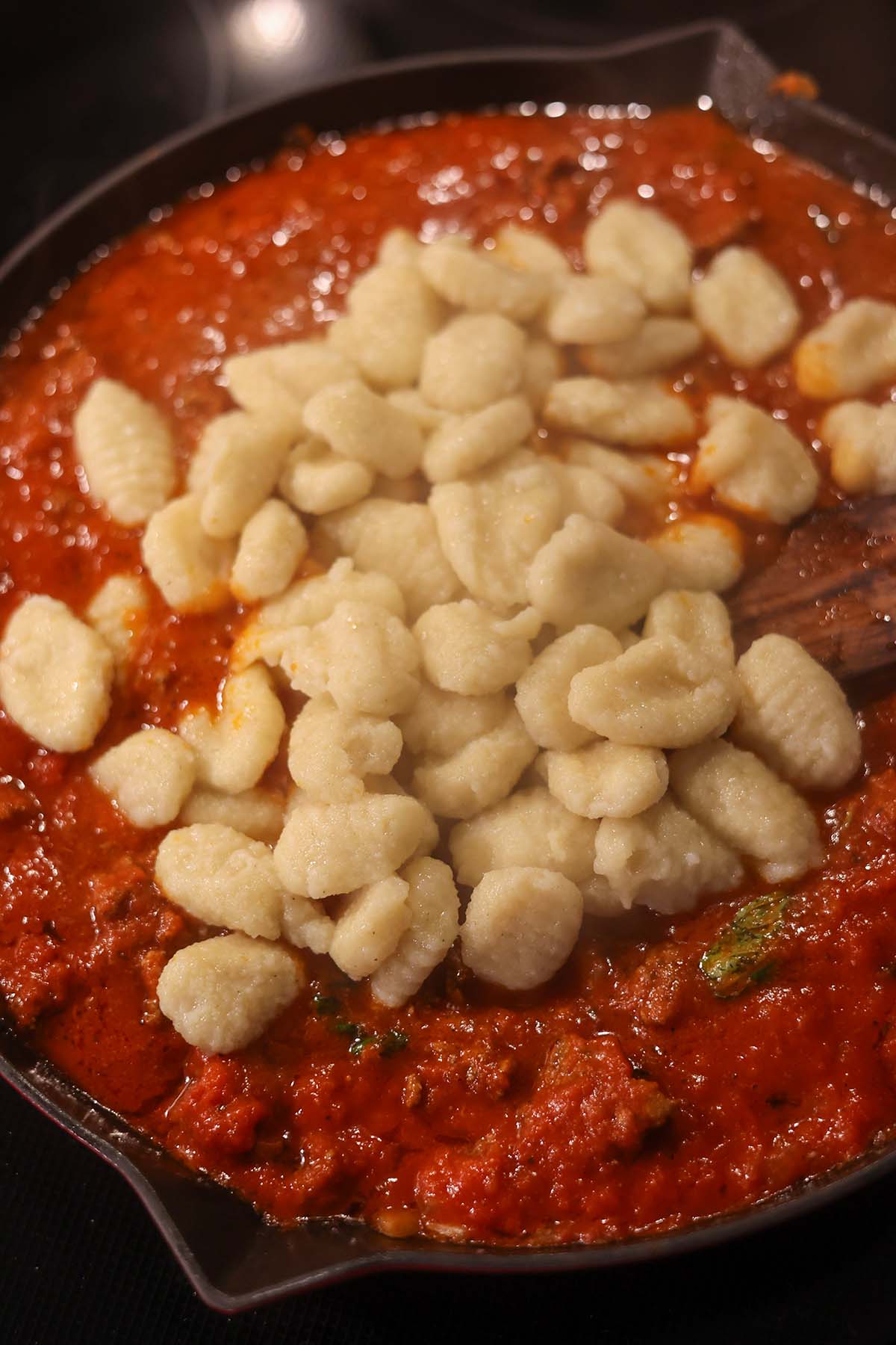 gnocchi being added to the meat sauce.