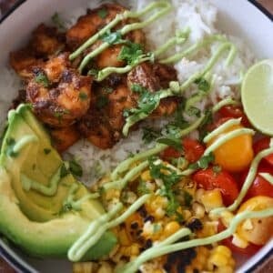 shrimp, rice, corn, tomatoes, avocado, lime wedge, and avocado sauce.