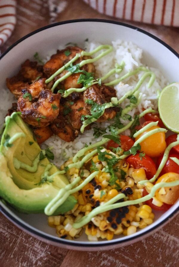 shrimp, rice, corn, tomatoes, avocado, lime wedge, and avocado sauce.