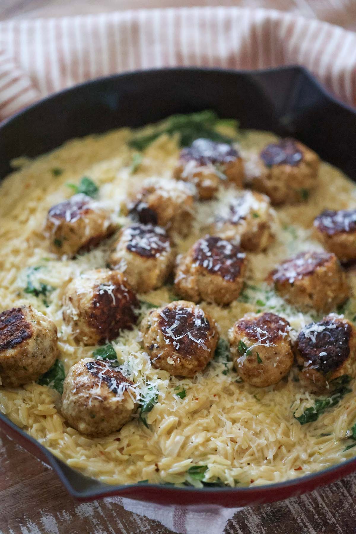 cooked meatballs on top of creamy orzo with spinach.